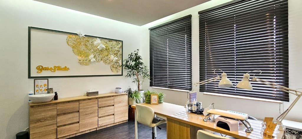 BASE STUDIO — stanowiska manicure, złote logo na ścianie, rośliny i jasne wnętrze salonu